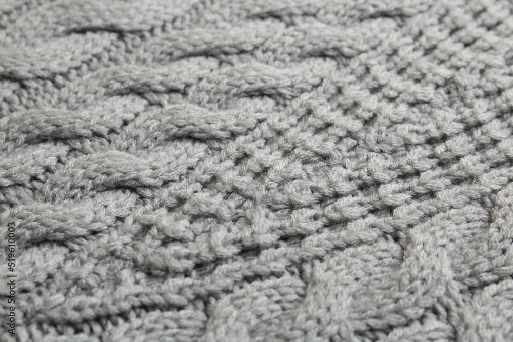 Grey knitted fabric with beautiful pattern as background, closeup
