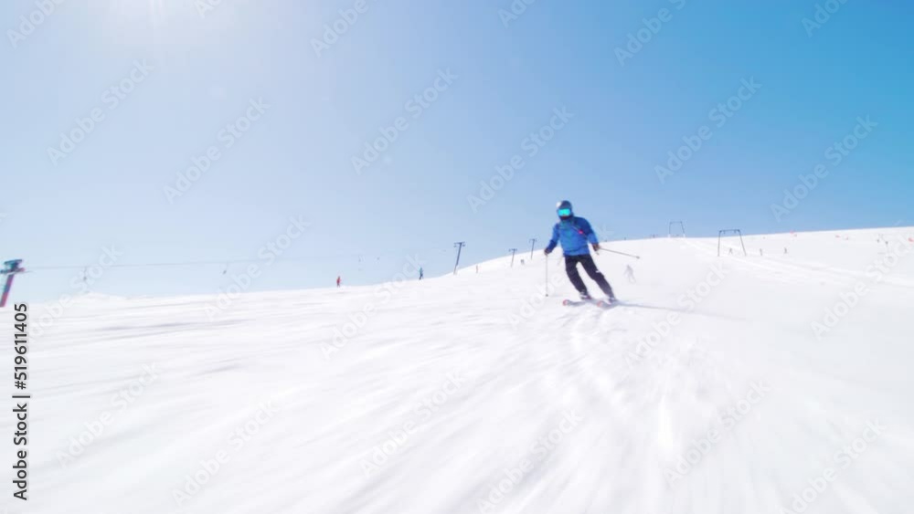 Skier skiing on slopes in winter ski center. Sun rays and lens flare visible. Skier skiing on slopes in winter ski center. Sun rays and lens flare visible.