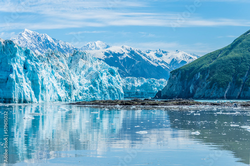 A view past an islet and the snout of the Hubbard Glacier into Russell Fjord in Alaska in summertime