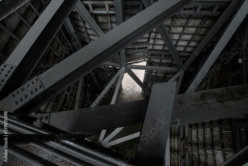Contrasting shot of a metal structure showing strong angles of the beams and rivets. light beams shining through adding to the dramatic effect. 