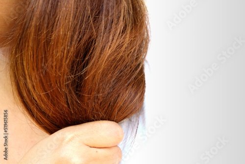 Asia woman wear white shirt holding her long hairs that make color treatments that maybe reason make hairs have problem (split end) .Should care or cut end of hairs. On plain background