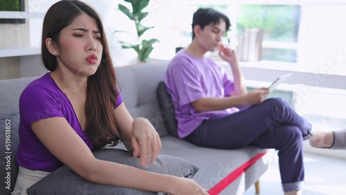 young asian woman sitting on the sofa at home with irritable mood and anger on her boyfriend