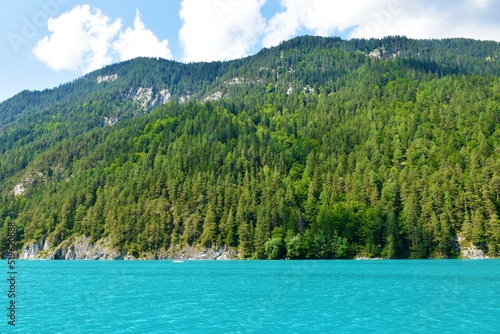 Fototapeta Naklejka Na Ścianę i Meble -  Forest covered mountains in Gailtal Alps in Carinthia, Austria and turquoise colored Weissensee lake bellow