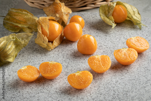 Картината върху платно Fresh whole and halved Cape gooseberry, Physalis Peruviana, with husk on wooden