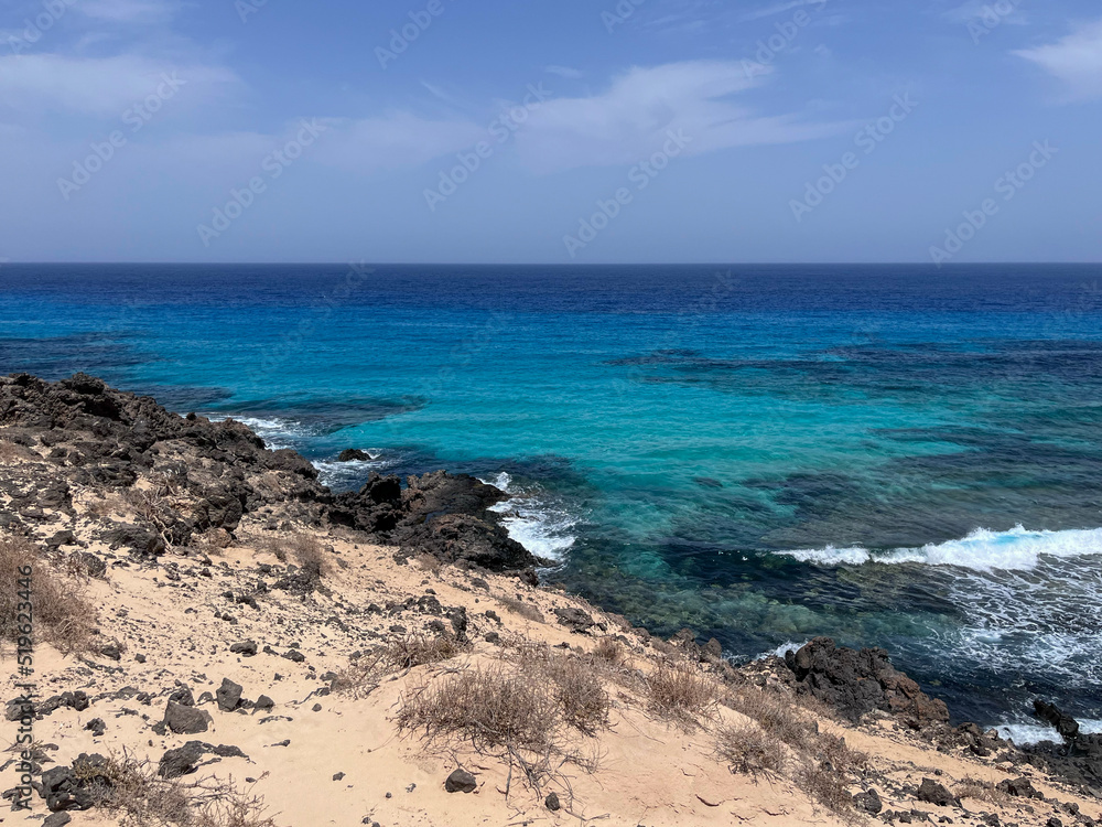 summer day on the rocky and sandy beach with turquoise blue waves
