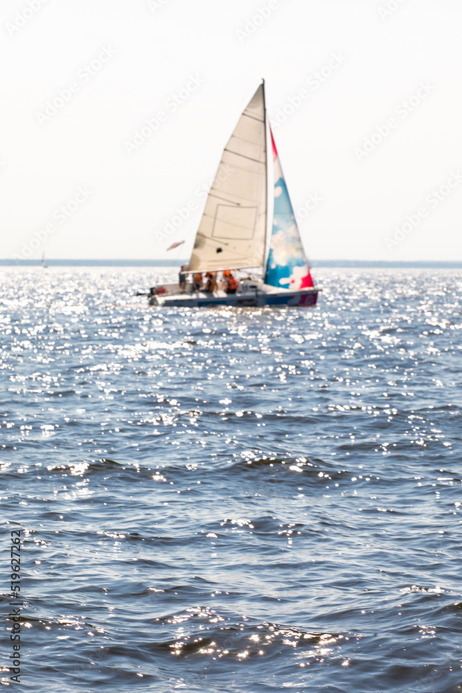 Blurred yacht with raised sails. Defocused sailing boat at full speed on the horizon of the sea on a sunny day