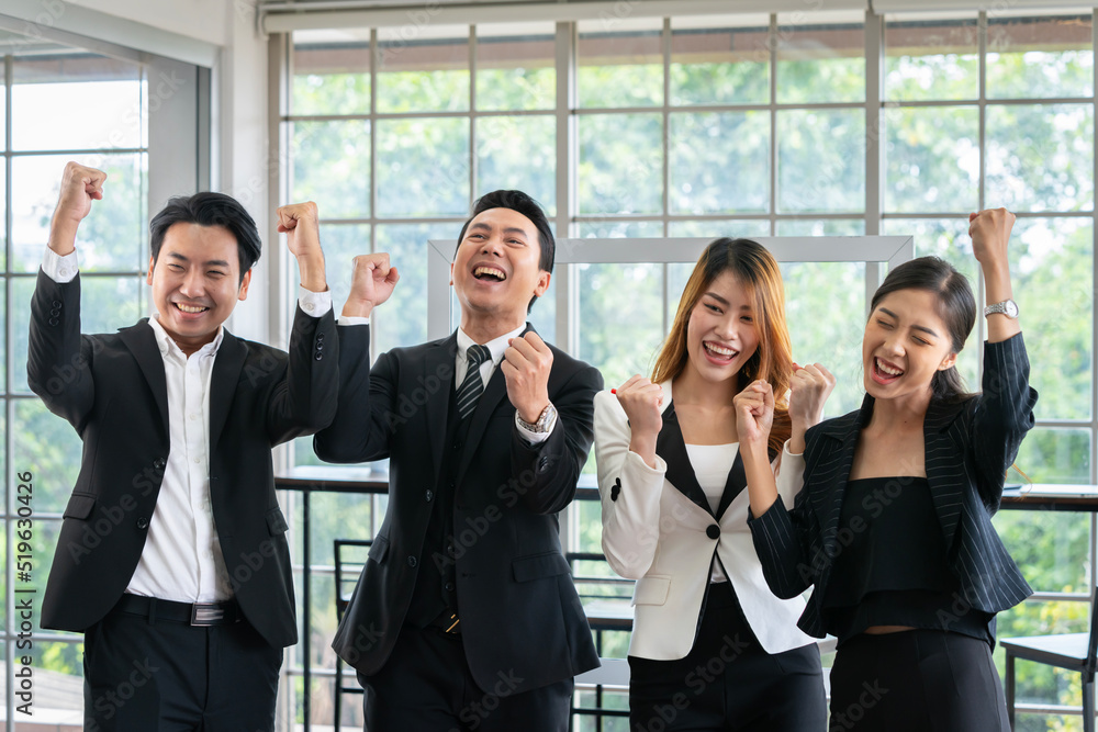 A group of young businessmen in suits, Asians, are determined and excited about their work. and encourage the team members by raising their hands happily A group of young businessmen in suits, Asians, are determined and excited about their work. and encourage the team members by raising their hands happily