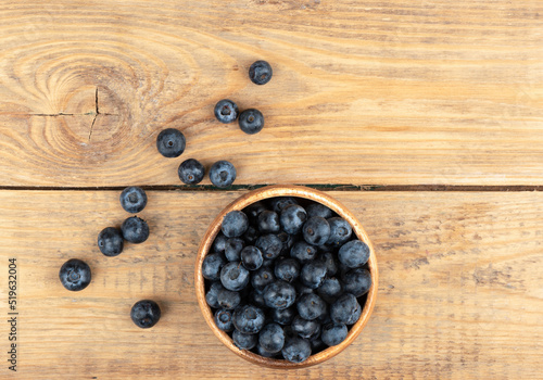 Top view of blueberries or bog whortleberry on a wooden background.