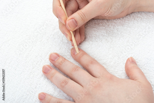 Young woman pushes back the cuticles on her nails with an orange stick. photo