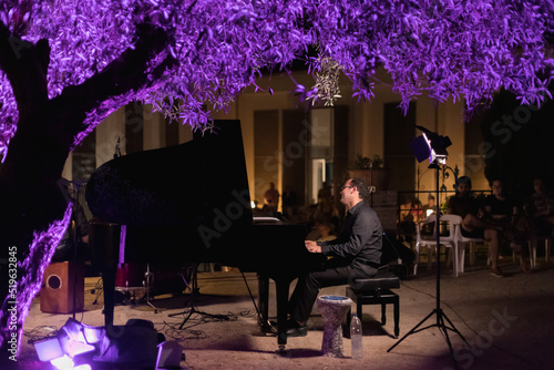 happy pianist playing outdoors in the evening, audience in the background