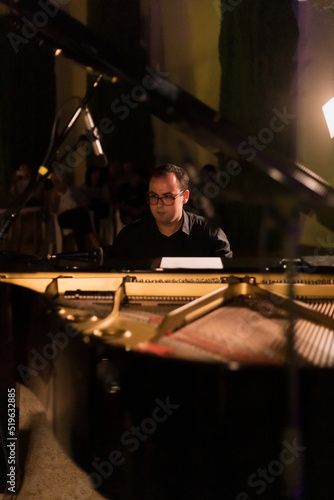 man playing grand piano at a night concert, vertical image