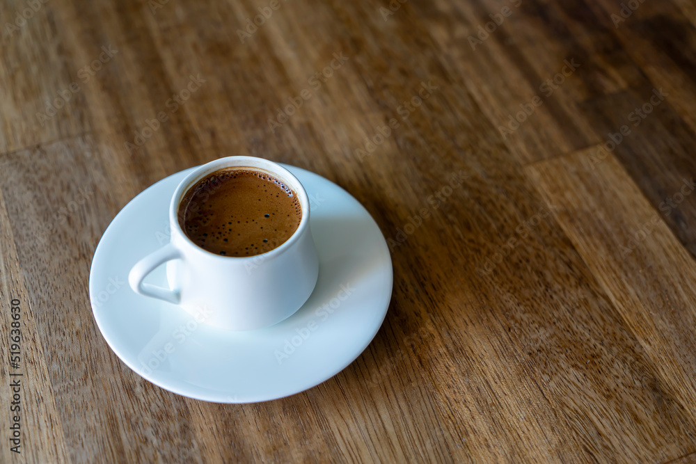 Selective focus on a white cup of turkish coffee on wooden table background with copy space. Noise effect and grainy texture. Selective focus on a white cup of turkish coffee on wooden table background with copy space. Noise effect and grainy texture.