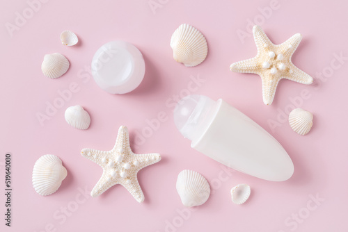 Roll on deodorant antiperspirant, sea stars and shells over pastel pink background. Sea minerals toiletries and cosmetics for body care. Personal hygiene items concept.