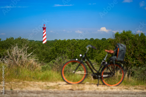 Lighthouse in Holland. Bike with backpack on the way. Cycling in Netherlands, Zeeland, West Schouwen. photo