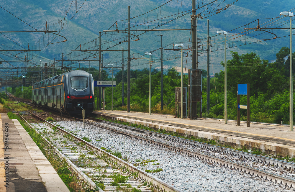 Fototapeta premium Train arrives at regular rural train station in Italy.
