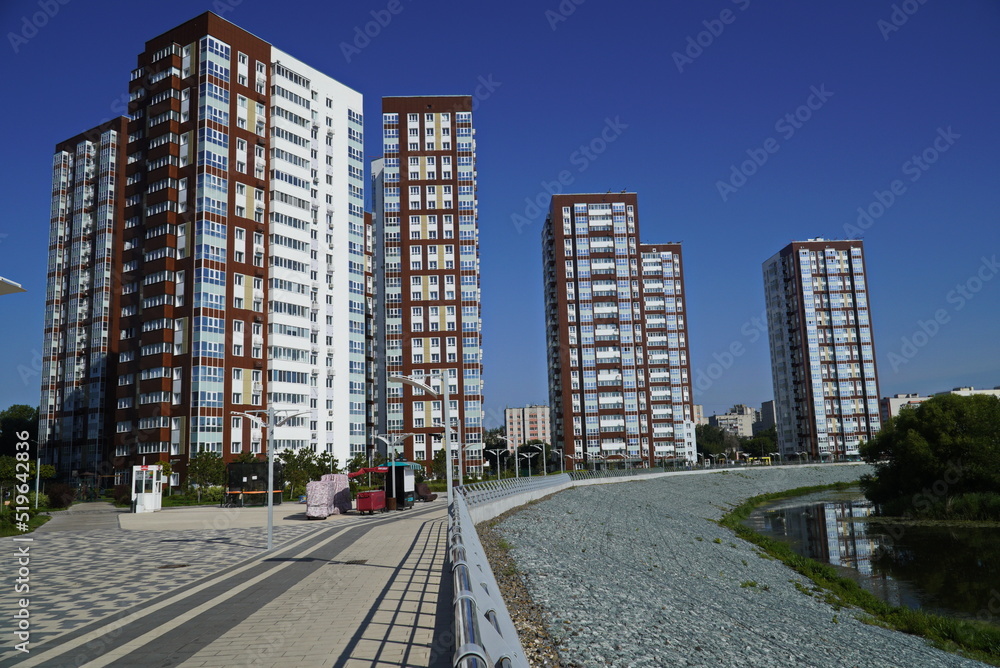 Modern construction, new neighborhood. Modern beautiful new buildings. Colored wall on the background of blue sky