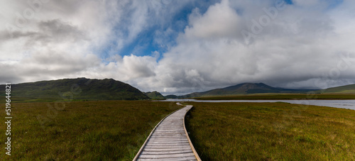 panorama landscape of the Claggan Mountain Coastal Trail bog and boardwalk with the Nephir mountain range in the background