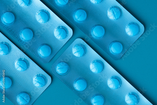 Four blisters with blue pills on a blue background. Blisters are arranged diagonaly.