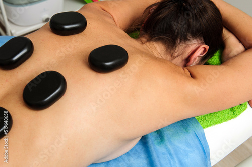 Close-up view of male masseur massaging back and shoulder blades of female lying on massage table at spa salon. Beautiful young woman with perfect skin getting relaxing massage.