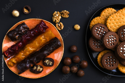 Churchkhela is a sweet delicacy of nuts in juices thickened with flour. Georgian churchkhela in a plate on a dark table with nuts. Close-up photo