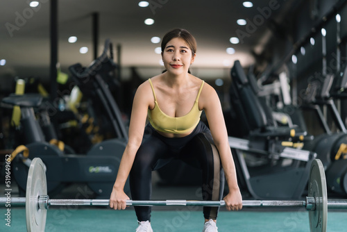 Beautiful Asian woman working out in the gym to stay fit and strong and gain beautiful muscles by lifting weights.