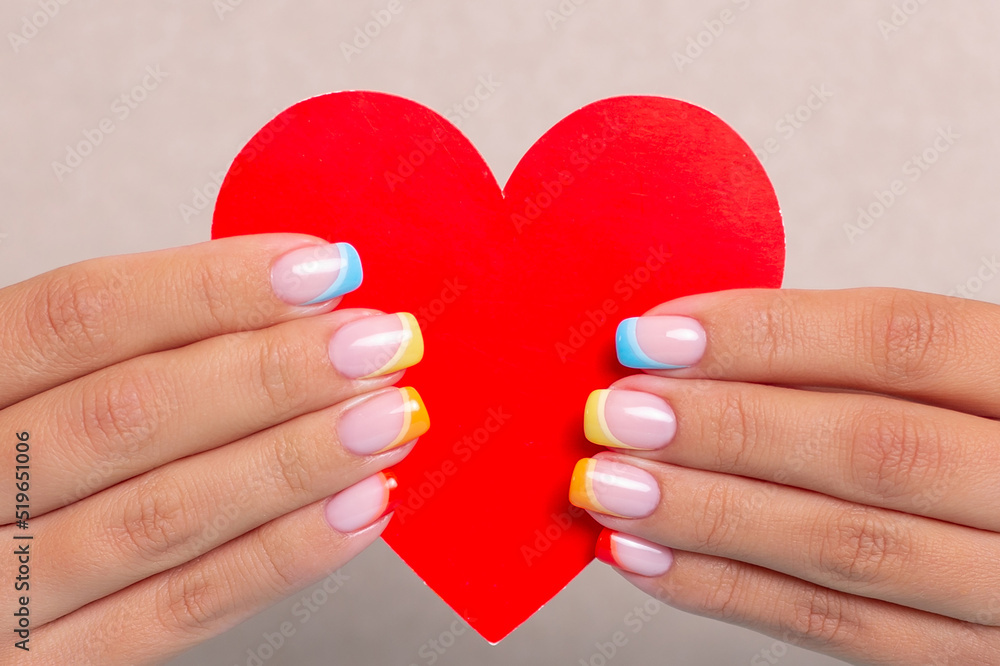 Obraz premium Beautiful female hands with colourful manicure nails with rainbow design