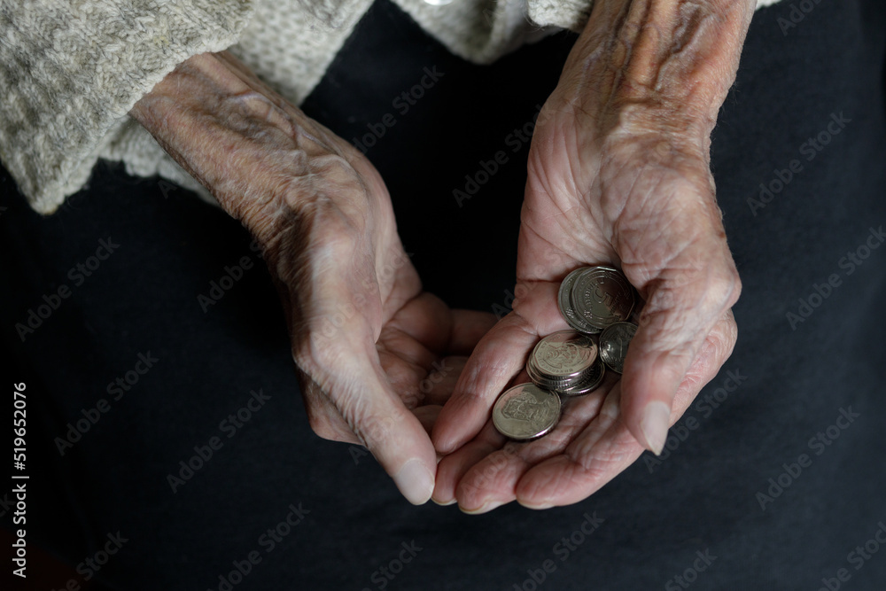 Obraz premium A woman's hands hold several Ukrainian hryvnia coins. Pension, poverty, social problems and the topic of old age. Preservation.