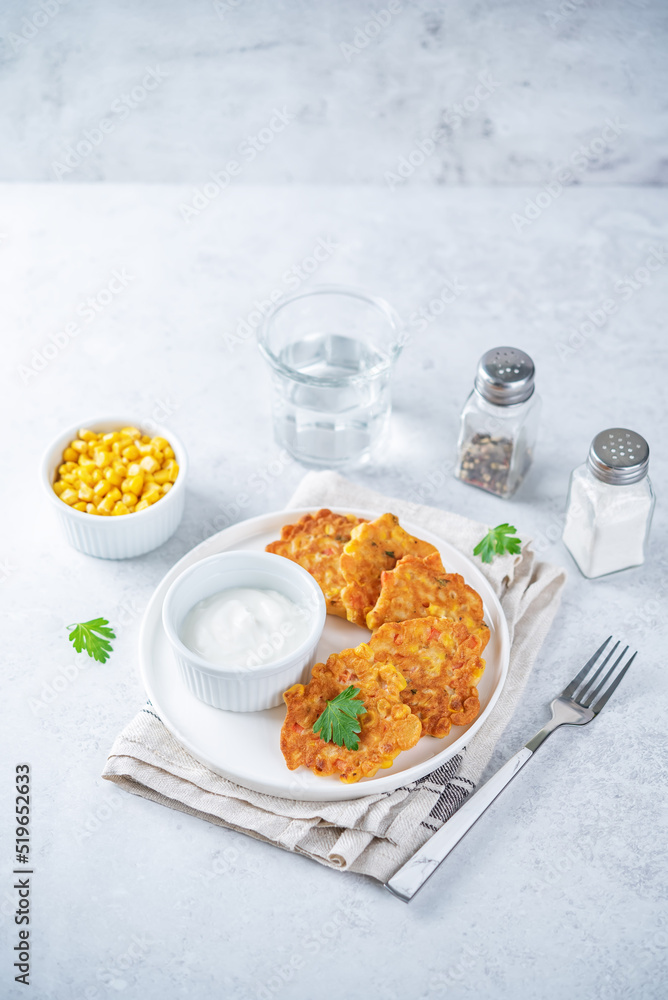 Corn fritters in a plate with sour cream sauce Corn fritters in a plate with sour cream sauce