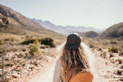 woman walking in karoo desert with cap & blond hair photo