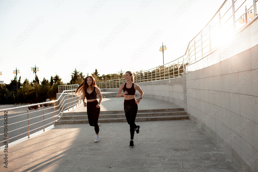 Group of slender girls running on the street against the background of a beige wall. People do heilth exercises. sports and fithess lofestyle for healthy people.