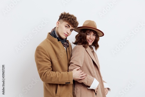 a man and a woman posing on a white background in an autumn coat put their hands in their pockets and sweaters, gently looking forward