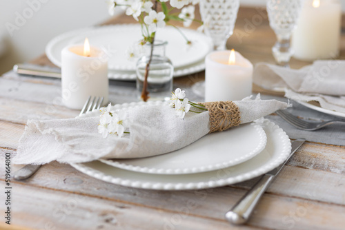 Rustic zero waste wedding decor with natural elements. Wooden table, candles, linen napkins, branches with green leaves. Eco-friendly decoration for the special dinner. Romantic and cozy place