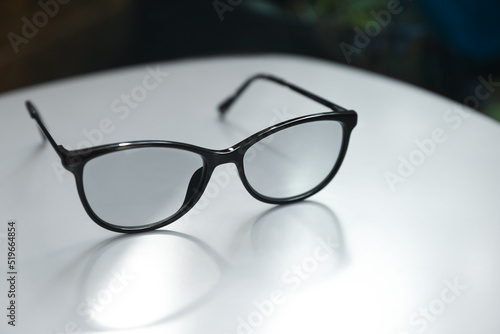 Stylish black eye glasses on white table, closeup