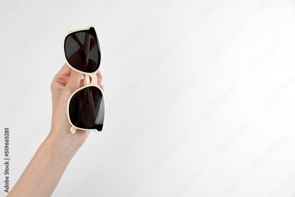 Woman holding stylish sunglasses on white background, closeup. Space for text