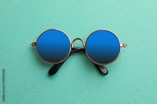 New stylish elegant sunglasses on turquoise background, top view