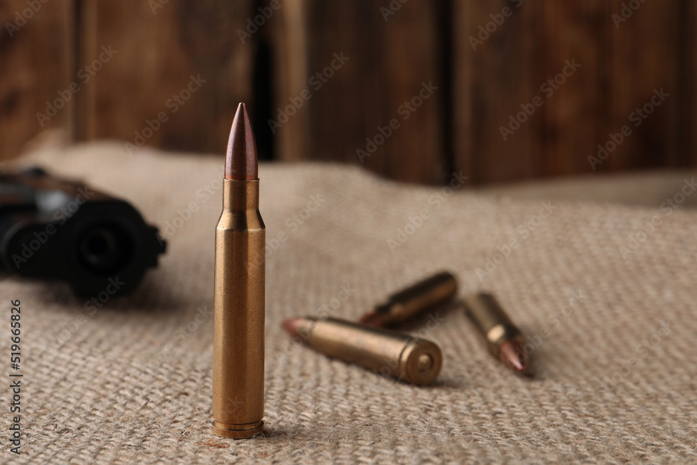Many brass bullets on burlap, closeup. Space for text