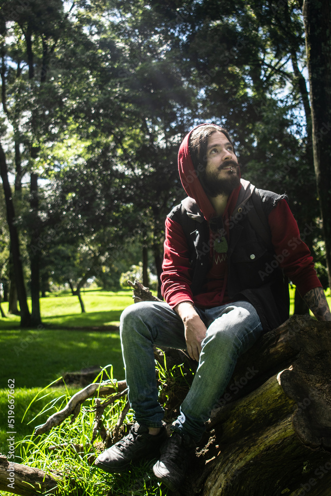 Joven con barba descansando en un parque y observando la naturaleza