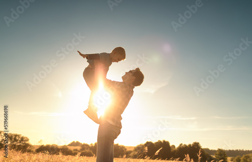 Happy father and son. Father lifting his child up to the sunset sky. Fatherhood, and parenting concept. 