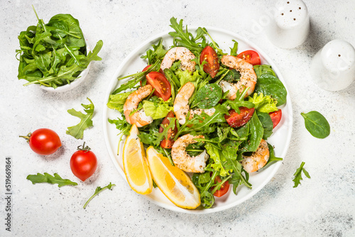Shrimp salad with vegetables and leaves. Top view on white table. photo