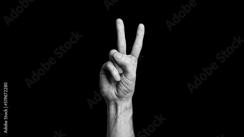 Hand making a victory sign, two fingers, showing two, on the black background, peace