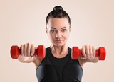 Sporty woman exercises with dumbbells. Good shape and health fitness woman weight training standing pose smile to camera.