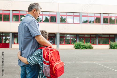 фотографія Happy dad hugs the child of the schoolboy and escorts him to school at the beginning of the lessons