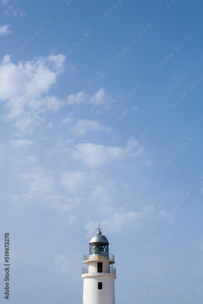 tip of a white lighthouse with a weather vane on the roof, a blue sky in the background with some clouds, Cavalleria lighthouse,  Menorca, Spain, copy space