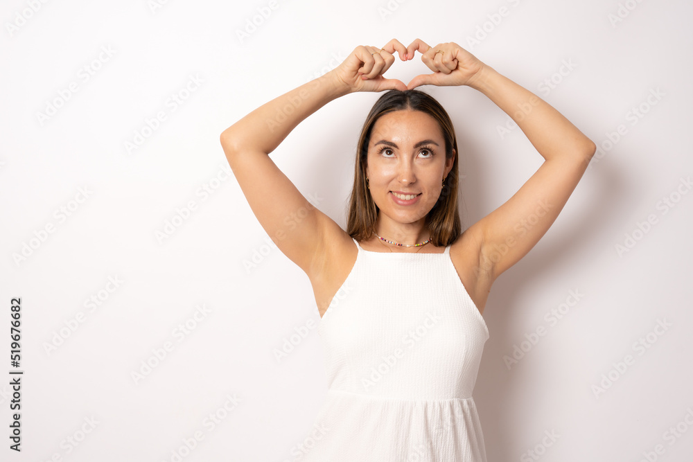 Portrait of lovely charming brunette girl making love symbol heart figure with fingers over head looking up isolated on white background Portrait of lovely charming brunette girl making love symbol heart figure with fingers over head looking up isolated on white background