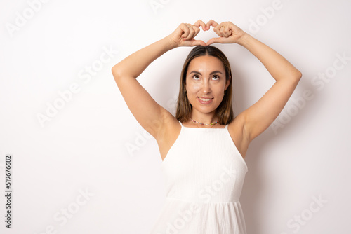 Portrait of lovely charming brunette girl making love symbol heart figure with fingers over head looking up isolated on white background