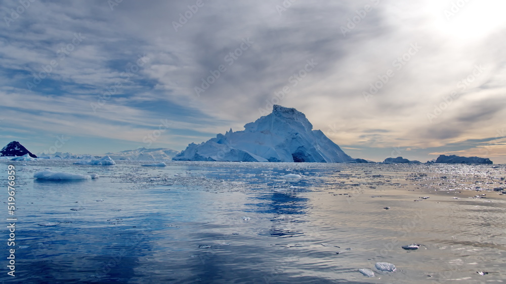 Small bits of ice floating in Cierva Cove, in front of a massive iceberg, Antarctica