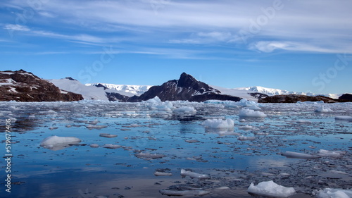Small bits of ice floating in the bay in front of snow covered mountains at Cierva Cove, Antarctica
