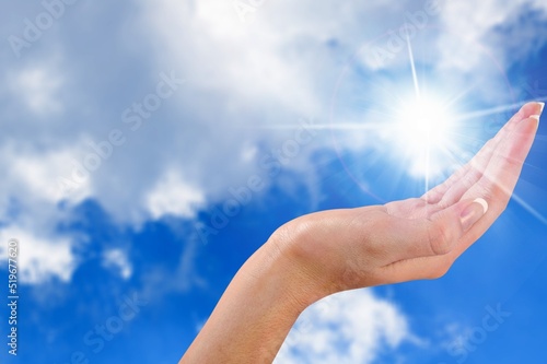 Human hand to sun on sky background