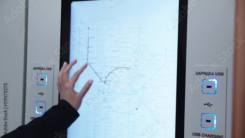 Woman is touching the interactive metro map and choosing the station shodnenskaya in russian. subway car wall with illumination, sensor display and usb charging with title in both russian and english. photo