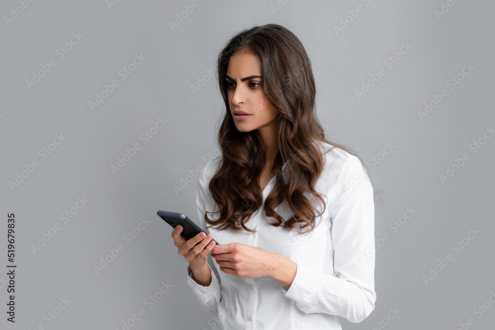 Serious business woman looking at the phone screen, reading message on smartphone, typing text on smart mobile phone. Female freelancer chatting by mobile phone. Serious business woman looking at the phone screen, reading message on smartphone, typing text on smart mobile phone. Female freelancer chatting by mobile phone.